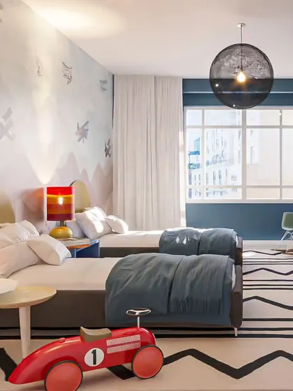 A shared kids' room with an airplane-themed wall mural and a bold patterned rug, perfect for little adventurers.