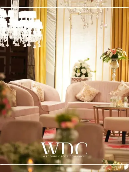 A comfortable and chic lounge area with plush pastel pink sofas and elegant chandeliers, providing a perfect space for guests to relax and mingle.