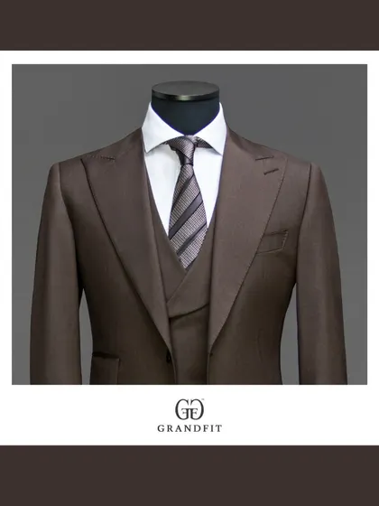 A detailed view of a rich brown three-piece suit, focusing on the peak lapels and the coordinated waistcoat. This color offers a warm and distinguished option for business wear.