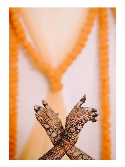 A creative detail shot of the bride's hands, with the simple background of marigold garlands adding a traditional touch.
