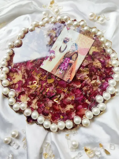 A beautiful round resin frame with a pearl border, filled with preserved varmala flowers and a wedding photo. A classic and elegant way to keep your memories close.