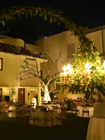 A wide-angle shot showing the full scope of the outdoor party setup. The greenery-wrapped chandelier serves as a beautiful focal point, tying the entire garden design together.