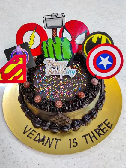 When you can't pick just one hero, you assemble them all. This Avengers-themed cake is topped with logos from multiple heroes like Captain America, Batman, and The Hulk, perfect for a third birthday party.
