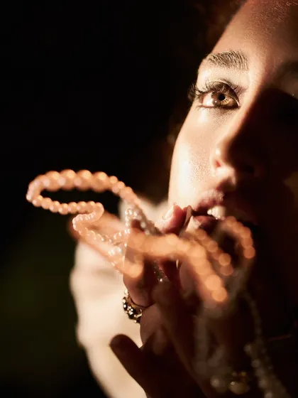 A macro shot focusing on the eyes and the creative use of a prop. The hard light source creates a sharp catchlight in the eye, drawing the viewer in.