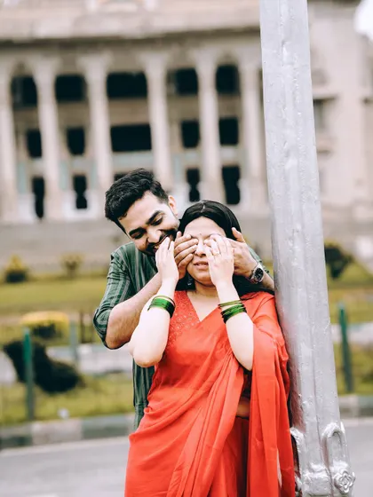 A playful 'guess who' moment on a city street, with the Vidhana Soudha in the background, blending fun and iconic Bangalore scenery.