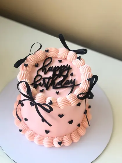 A cute pink and black vintage-style cake with delicate piping and little black hearts.