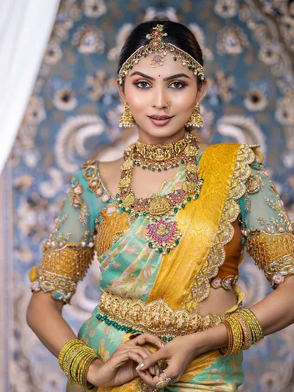 This bride looks absolutely regal. She is wearing a full bridal set with a matha patti, choker, and layered haram, all featuring intricate temple designs.