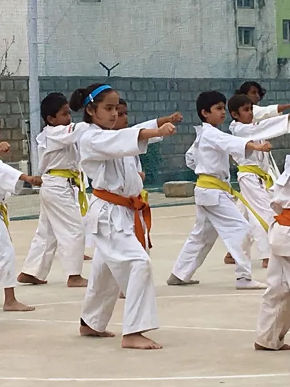 Young beginners with orange and yellow belts practicing basic punches. Every black belt starts with mastering these fundamental movements.