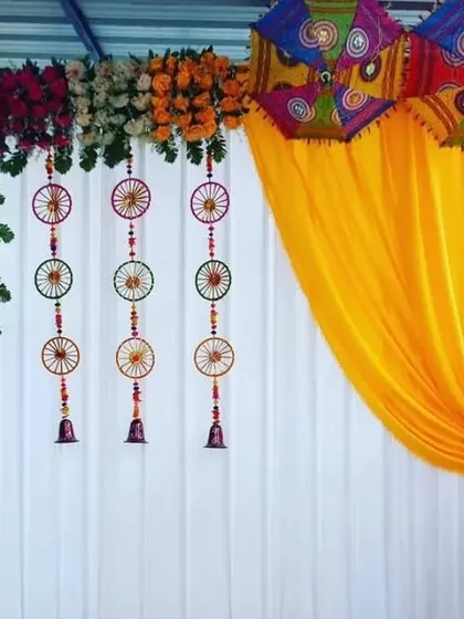 A simple backdrop detail showing a white curtain decorated with hanging wheel-shaped props and a floral border.