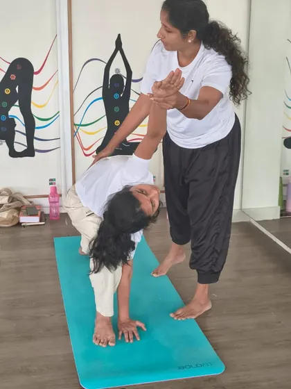 A teacher provides a gentle adjustment in Trikonasana (Triangle Pose), helping a TTC student find the correct alignment and deepen the stretch. This is the essence of our teaching methodology.