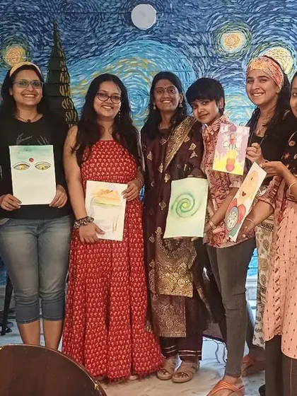 A group of happy participants from our "Awakening Shakti" art workshop, holding up the beautiful paintings they created.