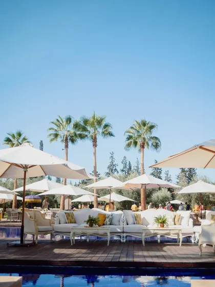 Chic white lounge furniture and umbrellas set up around the pool for the Haldi soiree in Marrakech.