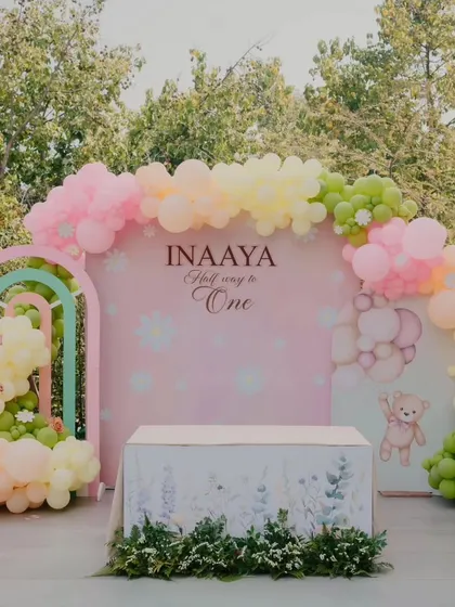 The full backdrop for the half-birthday party, showing a beautiful arch of pastel balloons and a custom-designed table covering.