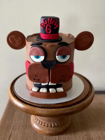 The full view of the Fazbear Freddy cake on a wooden stand.