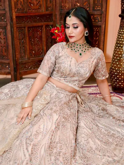 This model is wearing a light-coloured lehenga with a contrasting emerald green American Diamond necklace set. The matching maang tikka and ring complete this elegant party look.
