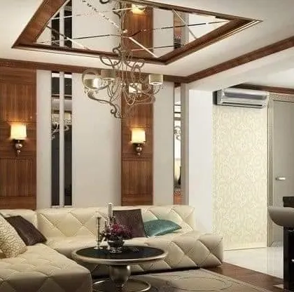 An elegant living room with mirrored panels and wood accents. The classic chandelier and quilted sofa add a touch of timeless luxury.