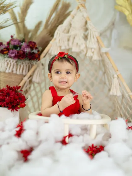A happy smile that shows the beauty of simplicity. The red outfit pops against the neutral, textured backdrop.
