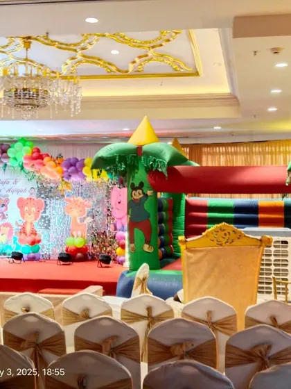 A wide view of a jungle-themed party, showing the stage decor and an inflatable bouncy castle for entertainment.
