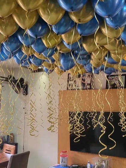 A dense ceiling of blue and gold helium balloons for a rich, celebratory look.