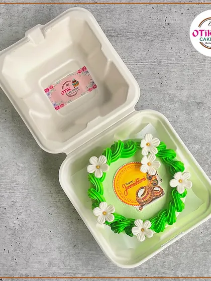 A lovely Janmashtami bento cake with a green floral wreath and an edible print of Lord Krishna. Perfect for a small, personal celebration.