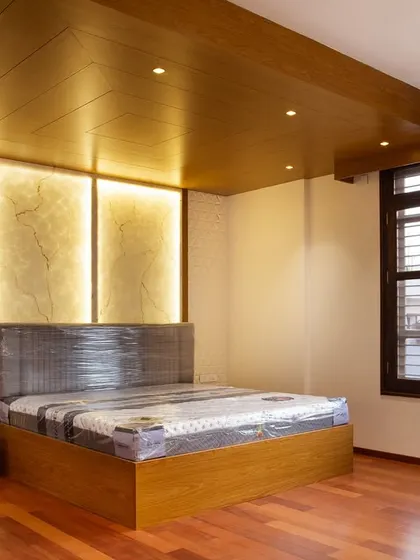 This master bedroom features a stunning backlit stone panel and warm wooden flooring. The large, discreet sliding wardrobe on the left is designed to be understated, keeping the focus on the room's luxurious architectural details.