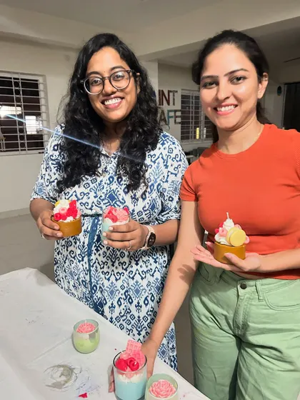 A repeat of two participants smiling with their finished cupcake and dessert-style candles.