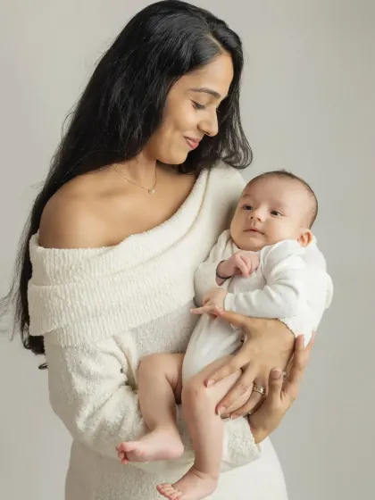 A stunning portrait of a new mother holding her baby. Her gentle gaze and the baby's curious expression make this a beautiful memory.