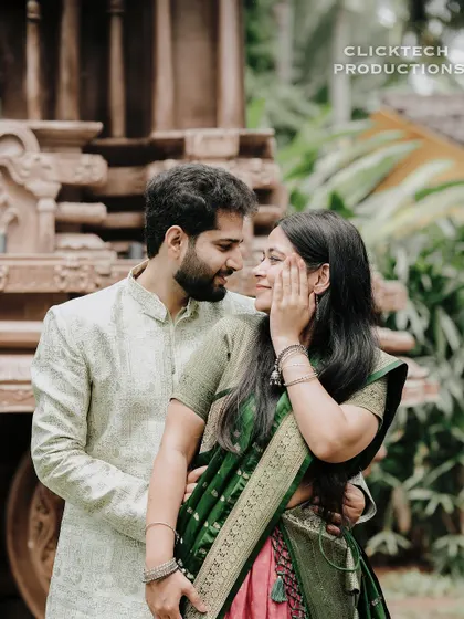 An intimate close-up of a couple in traditional green and pink outfits, sharing a tender moment.
