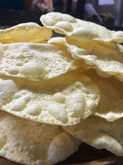 A pile of freshly fried, crispy papadums, ready to be served. These light, airy discs are an essential and much-loved part of any Kerala meal.