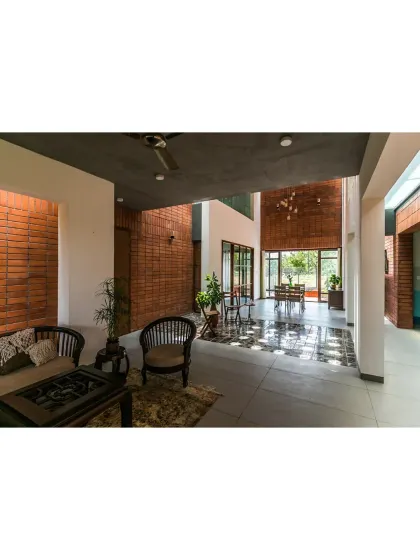 The living and dining areas of 'An Earthy Affair' are designed as a series of interconnected, open spaces that flow into one another. We used exposed brick walls and large glass doors to blur the line between the interior and the surrounding landscape, creating a home that breathes with its environment.