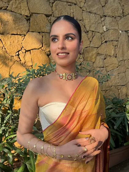 The makeup is subtle enough to let the intricate jewelry and beautiful saree shine, creating a harmonious and stylish look.
