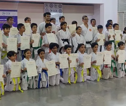 A large group of students from the Silicon City dojo pose together, holding up their certificates that mark their promotion to the next kyu rank.