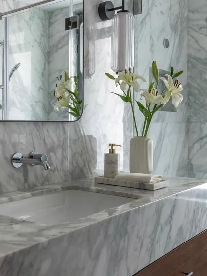 A detail shot of the marble countertop and wall-mounted faucet in a bathroom at the Parishram residence. Every detail is considered to create a sense of refined luxury.