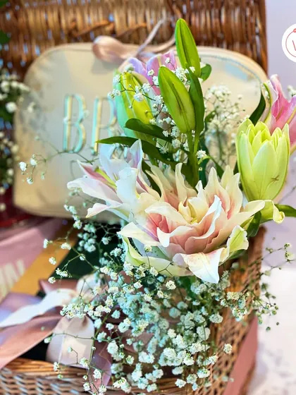 Another detail shot of the two-tiered wicker hamper, showing the fresh flowers and personalized pouch.