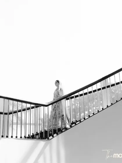 A minimalist black and white portrait. The bride's silhouette as she ascends a modern staircase creates a powerful, artistic image focused on lines, light, and form.