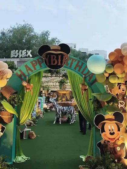 The same impressive jungle safari entrance captured during the day, showcasing the vibrant colors of the balloon arch and character cutouts.