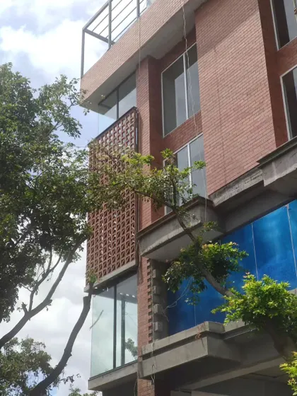 A commercial building under construction, featuring a terracotta screen wall that shields the glass facade from the harsh sun.