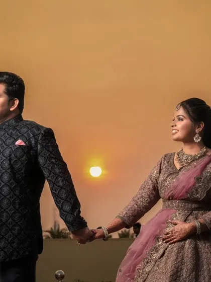 The couple holding hands and walking, silhouetted against the beautiful evening sky.