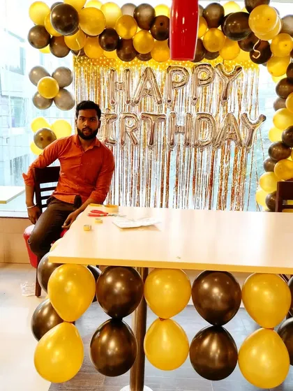 A simple yet classic birthday decoration for an office space. We created a backdrop with a golden fringe curtain and a balloon arch, along with 'Happy Birthday' foil letters. It's a great way to decorate a cafeteria or common area.