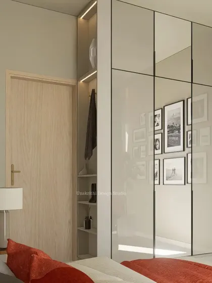 This bedroom design is a definition of 'pause'. The mirrored wardrobe doors make the space feel larger and brighter, reflecting the gallery wall on the opposite side. The open niche provides easy access to everyday items, blending functionality with a calm, down-to-earth aesthetic.