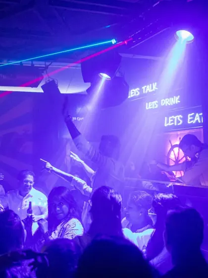 A wide shot of the club with hands in the air, showing the full effect of the music and lights on the crowd.