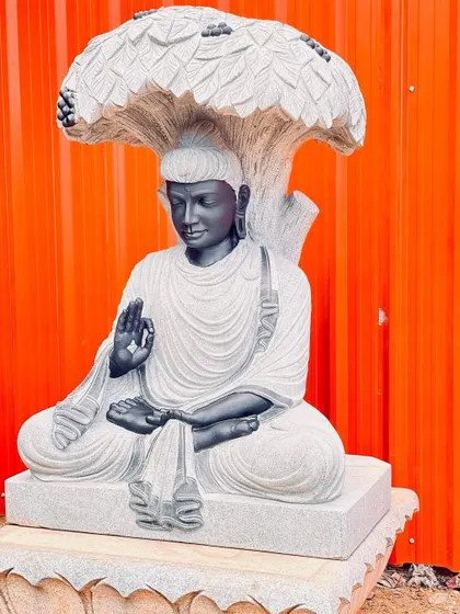 An intricately carved stone statue of Buddha sitting under the Bodhi tree. This is a large, statement piece for a spiritual or tranquil garden space.