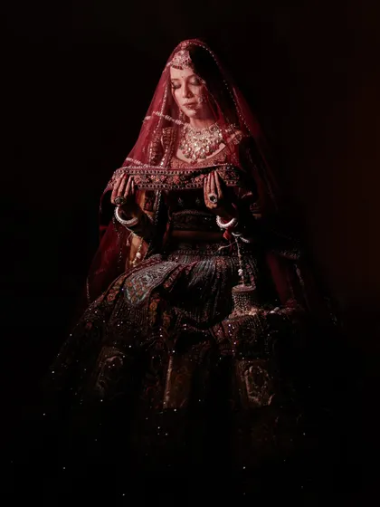 An artistic, low-light portrait of a bride. This moody and cinematic shot highlights the silhouette and rich texture of her bridal gown.
