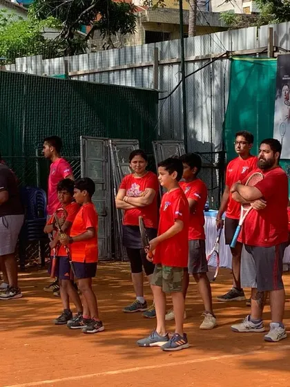 A group of our junior players in their red team shirts, listening intently to coaching instructions before a drill.