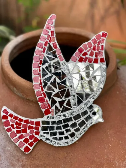 A mosaic bird wall hanger, made from red and mirrored tiles. This piece is designed to catch the light and create a sense of movement and freedom, perfect for any wall.