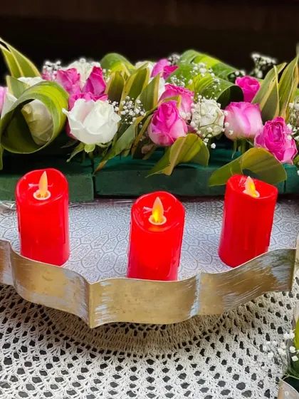 A gleaming urli adorned with vibrant blooms and red electric candles. This arrangement serves as a beautiful centerpiece, capturing hearts with its symphony of colors and fragrances.