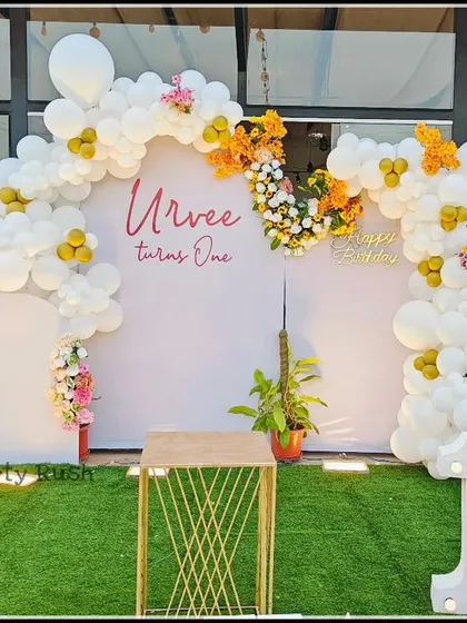 A full view of the elegant white and yellow floral balloon backdrop for Urvee's first birthday. This outdoor setup is perfect for a sophisticated yet cheerful celebration.