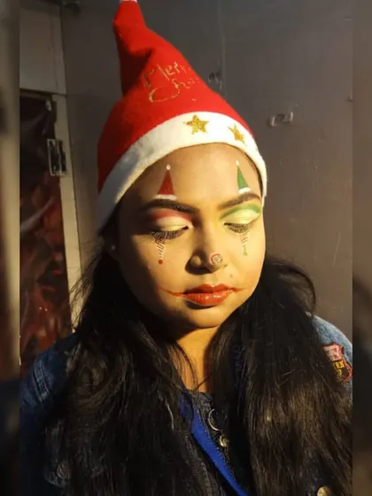 Another creative take on Christmas makeup. This student designed a jester-inspired look using festive red and green colors, demonstrating their skill in symmetrical design and character creation.