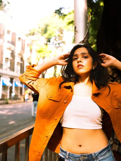 This shot captures a confident and direct gaze, using the bright sunlight and open street to create a fresh, energetic feel.