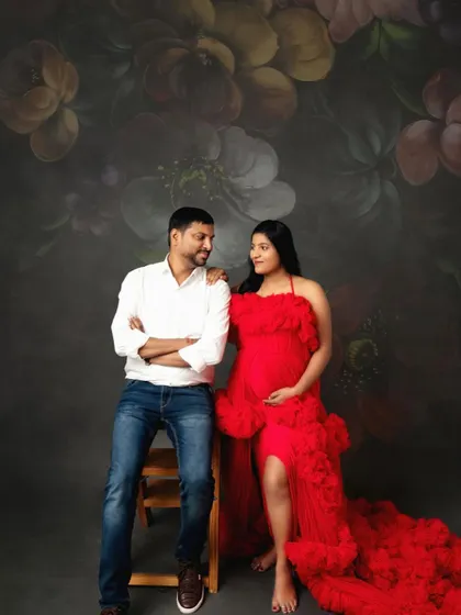 A maternity portrait that feels like a classic painting. The rich red gown against the floral fine art backdrop creates a dramatic and artistic celebration of motherhood.